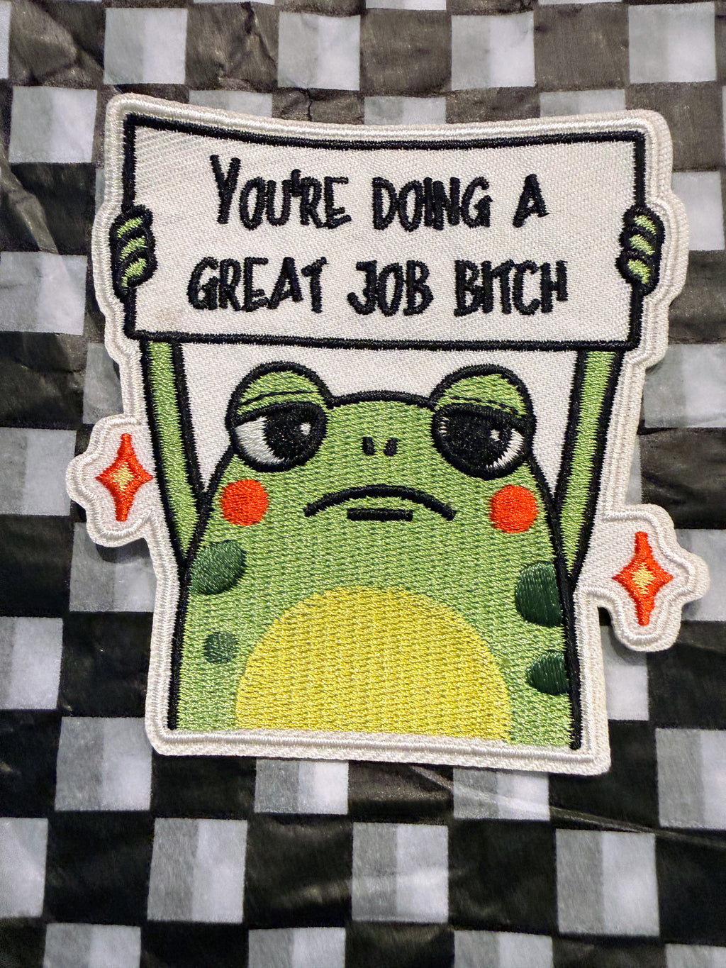 This hilarious embroidered iron on frog patch features a seriously unimpressed little frog holding up the message “You’re Doing a Great Job Bitch.” (Copy)