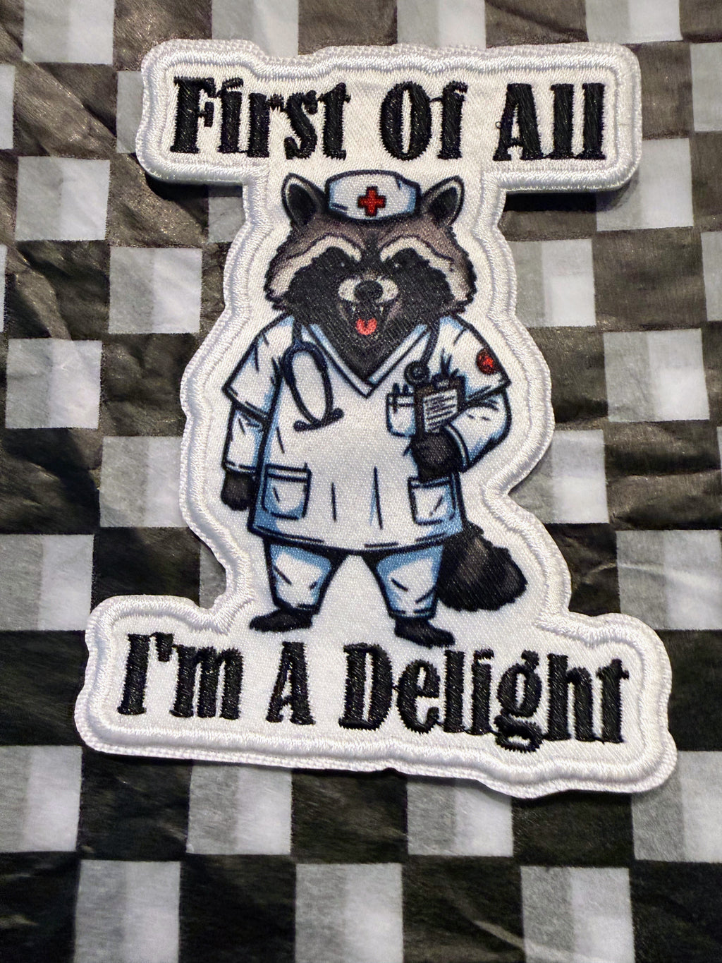 Cute, chaotic, and just a little bit sassy! This “First of All, I’m a Delight” iron on raccoon patch
