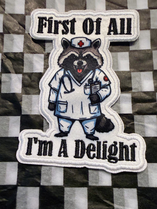 Cute, chaotic, and just a little bit sassy! This “First of All, I’m a Delight” iron on raccoon patch