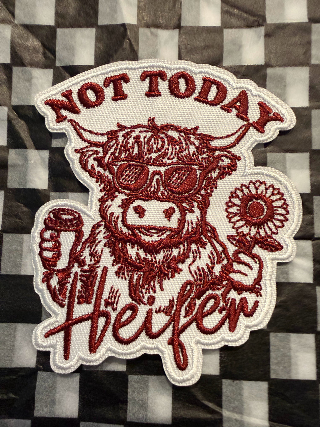 This “Not Today Heifer” embroidered patch features a sassy Highland cow rocking sunglasses, holding a drink in one hand and a cheerful sunflower in the other. Has rich red stitching against the crisp white background